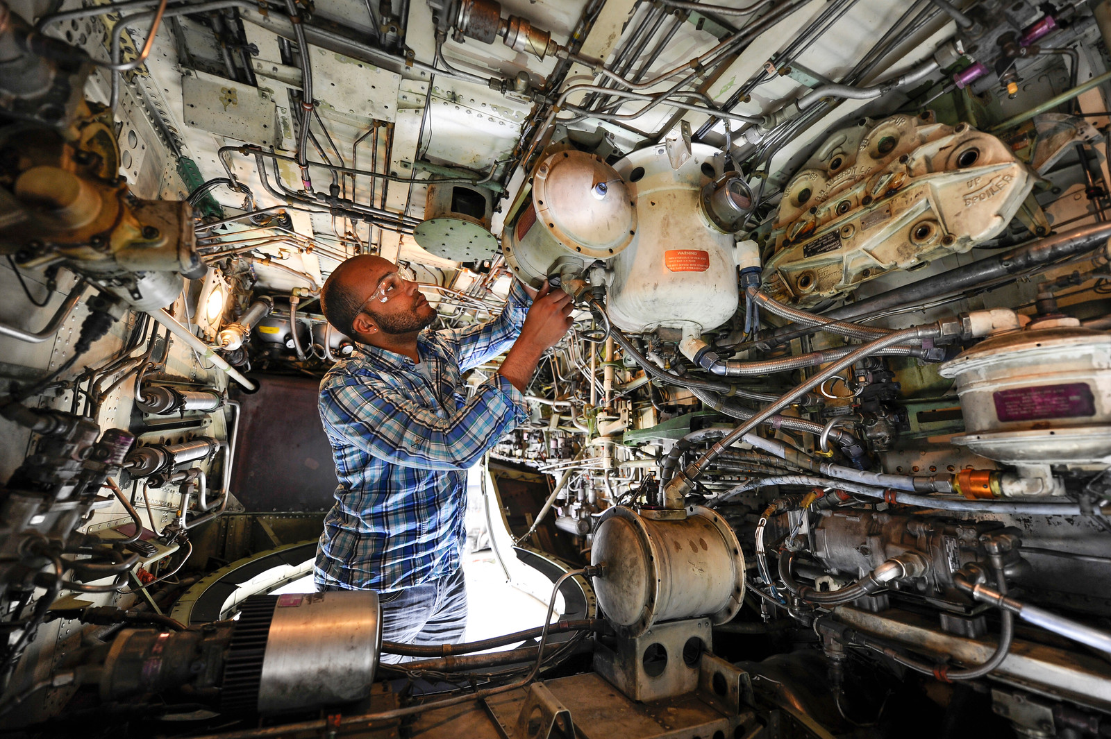 An aviation maintenance student fixing part of an airplane
