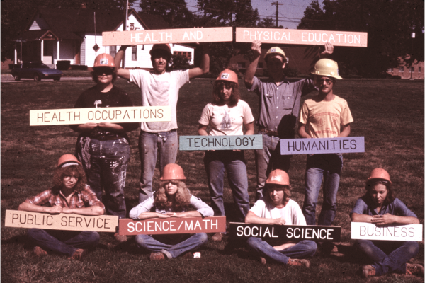 Students pose with academic department signs