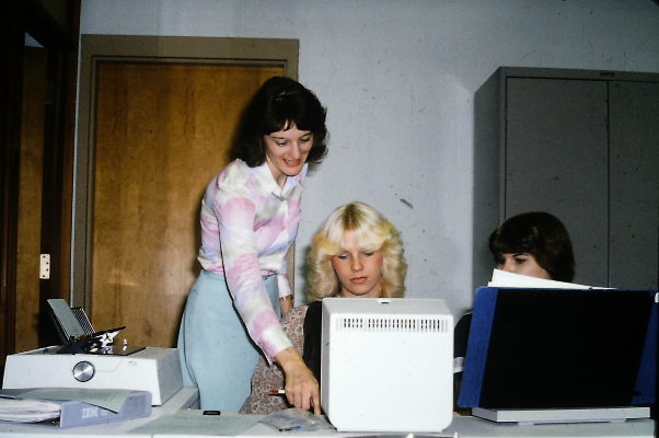 A professor is helping students on a computer terminal