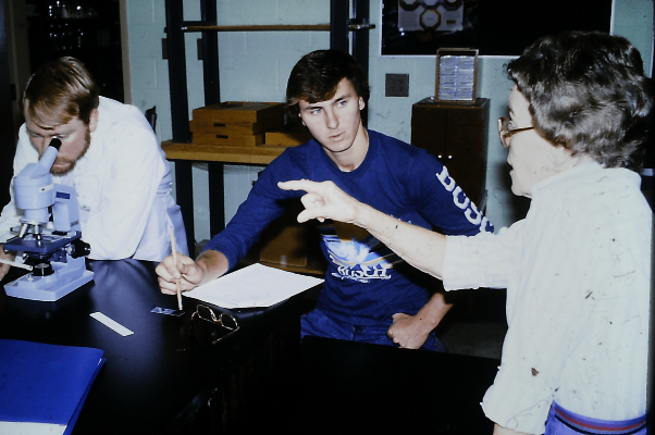 Biology instructor guiding students using a microscope