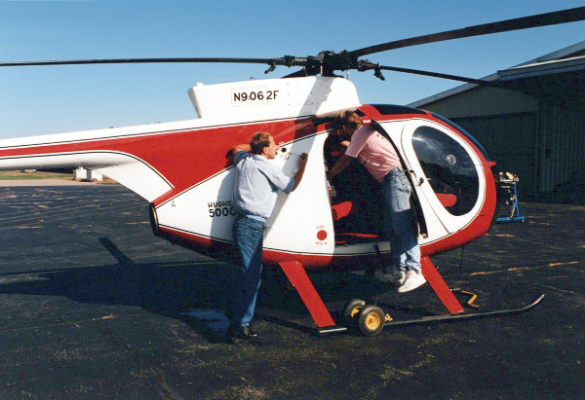 Aviation students inspecting Hughes 500C helicopter