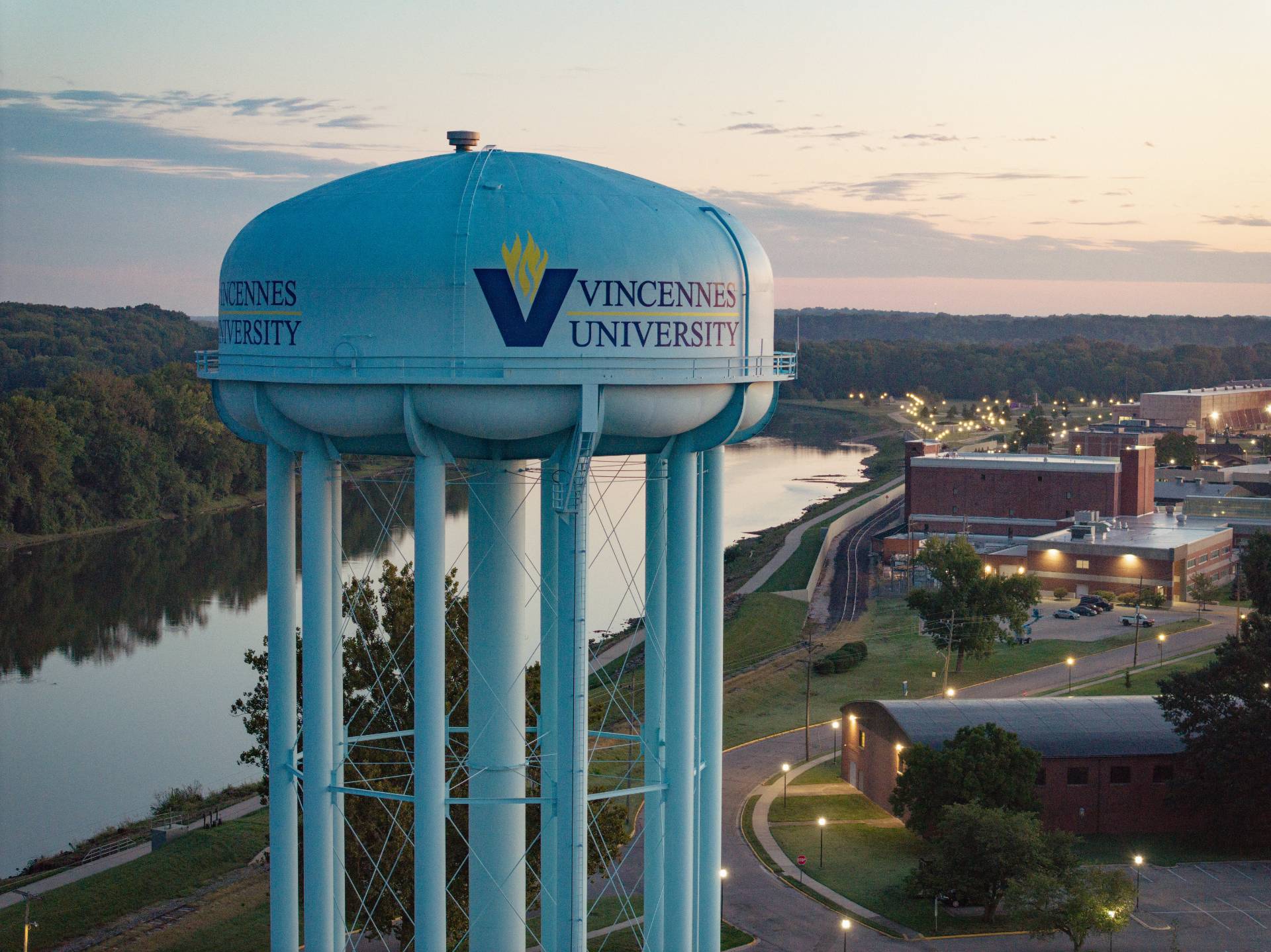 Vincennes University water tower overlooking campus and river at dusk.