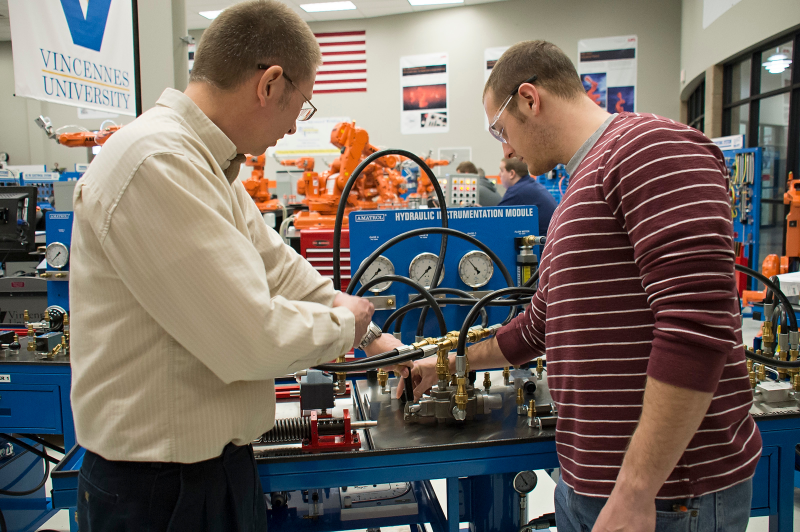 An instructor and a student examine a blue hydraulic instrumentation module