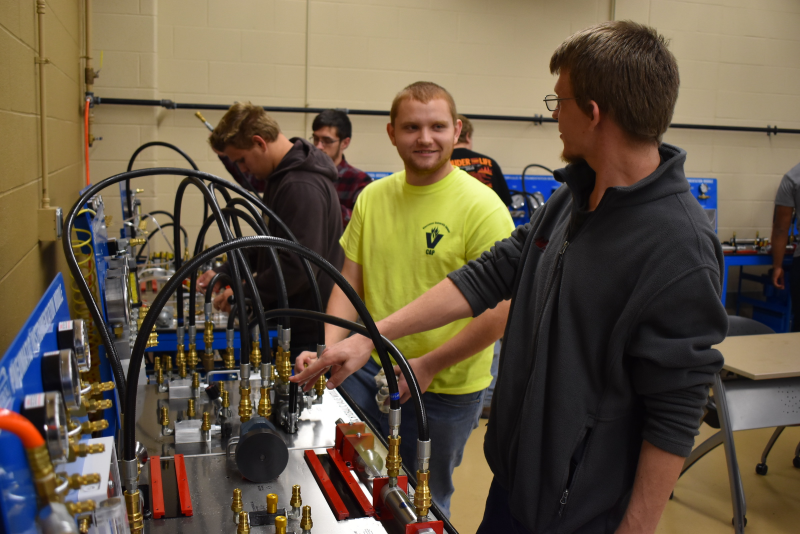 Students discuss and configure a pneumatic and hydraulic training bench