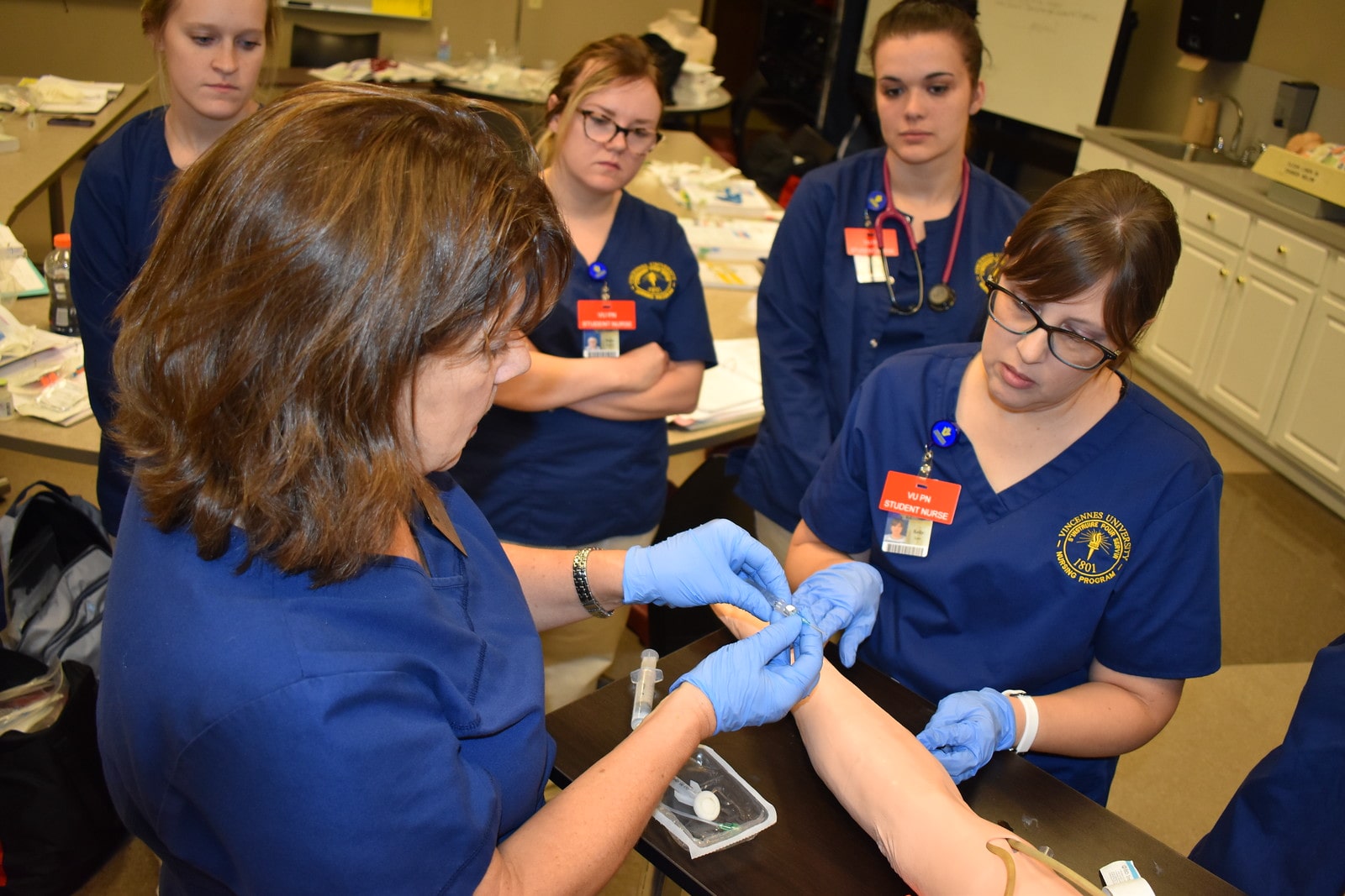 Vincennes University nursing students learning IV insertion techniques through hands-on simulation in a practical nursing lab.