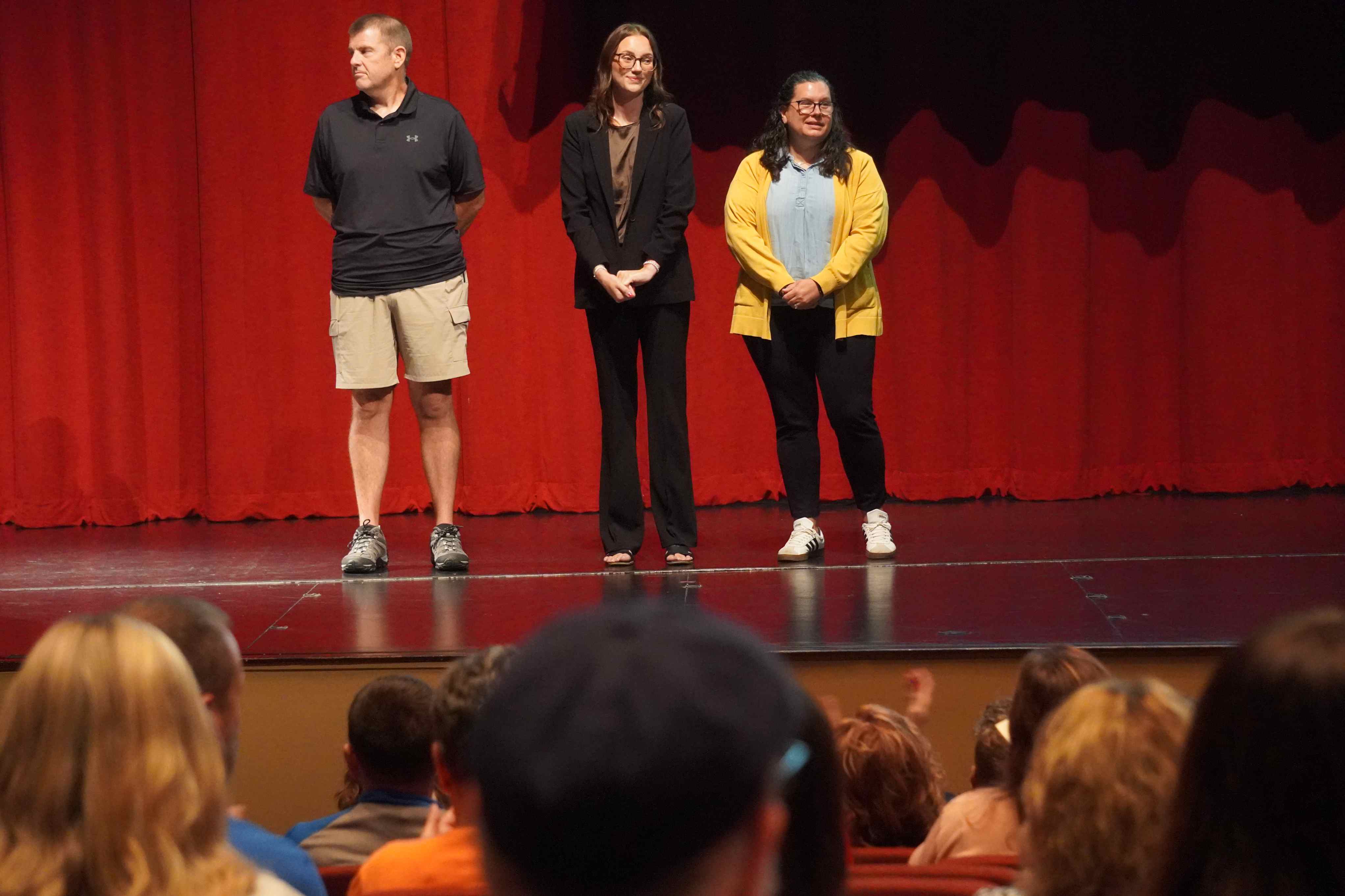 Ben Scott, Samantha Riley and Audrey Case standing on stage with a red curtain in the background