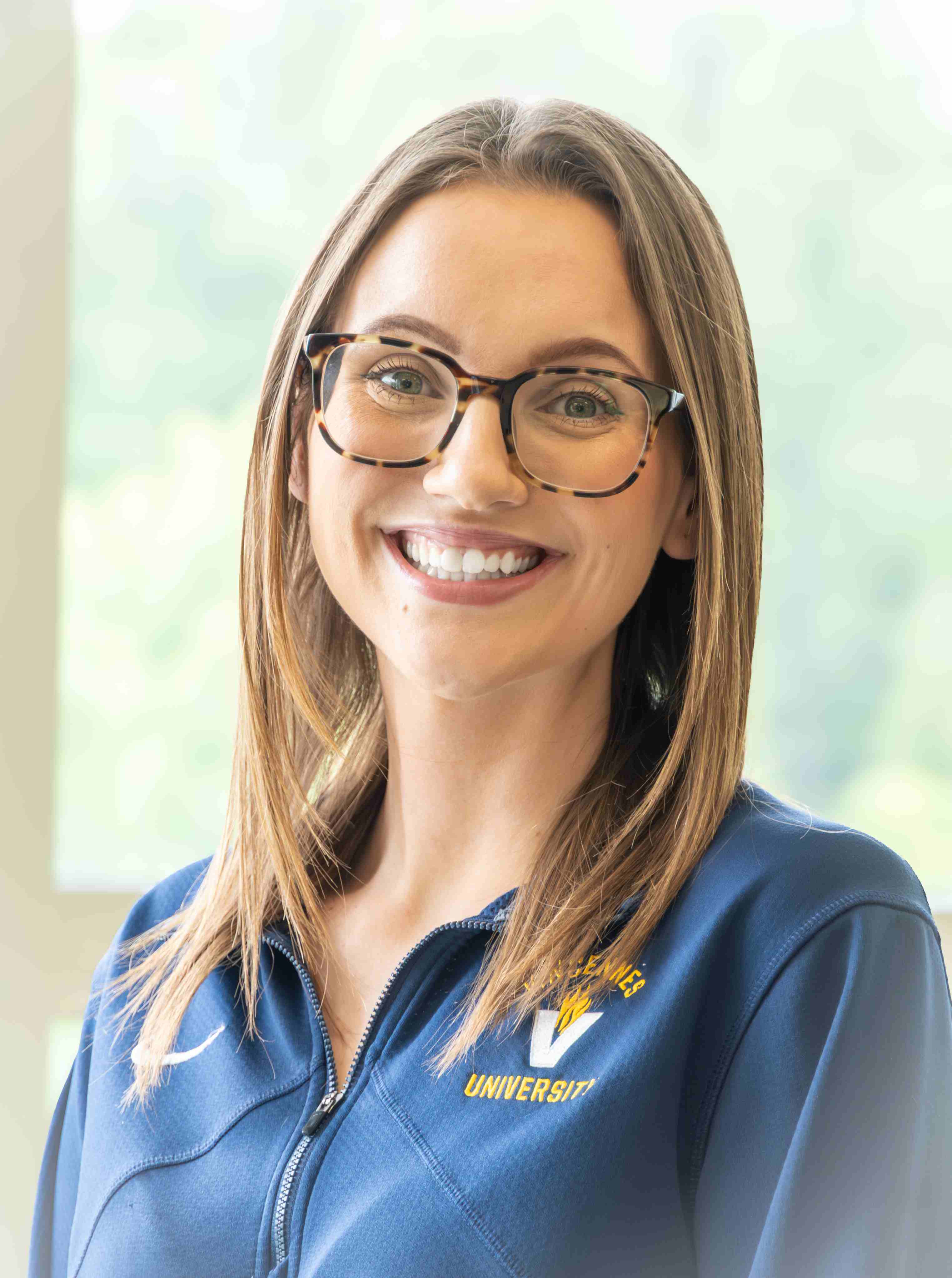 Headshot of Samantha Riley who wears glasses and has long, straight brown hair