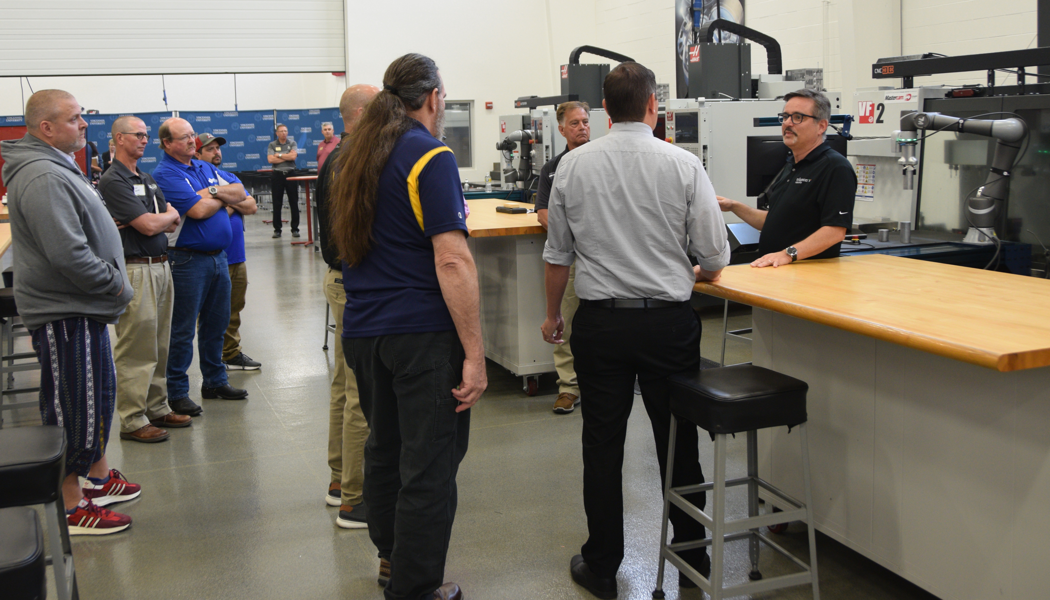 A group of CTE instructors surround CARA Director Paulo Dutra e Mello near a cobot at the Gene Haas Training and Education Center