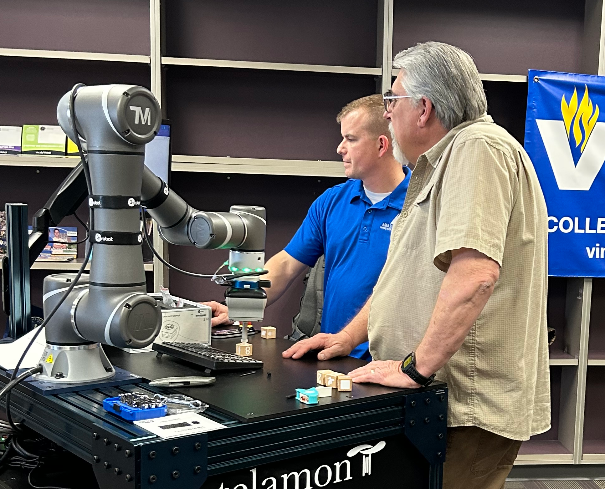 Two men use a collaborative robot during a training session.
