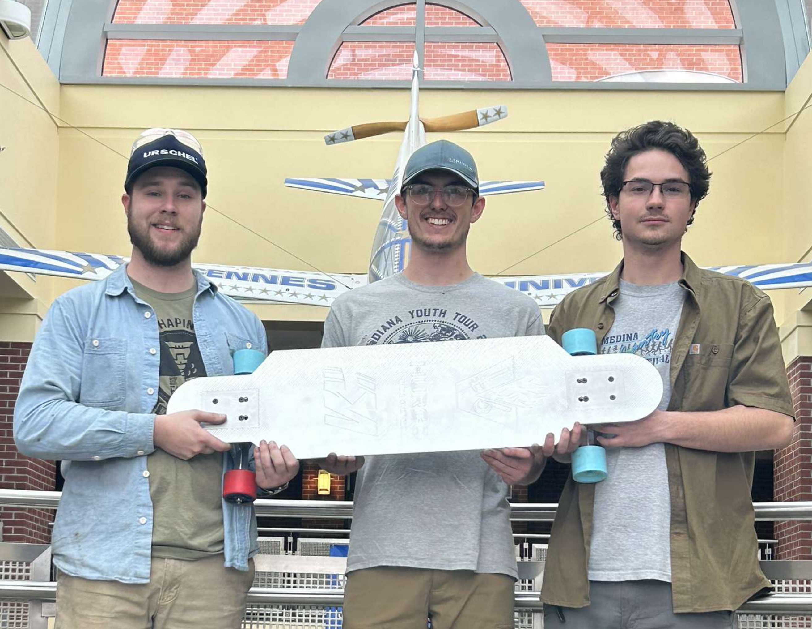3 male VU students holding winning electric skateboard