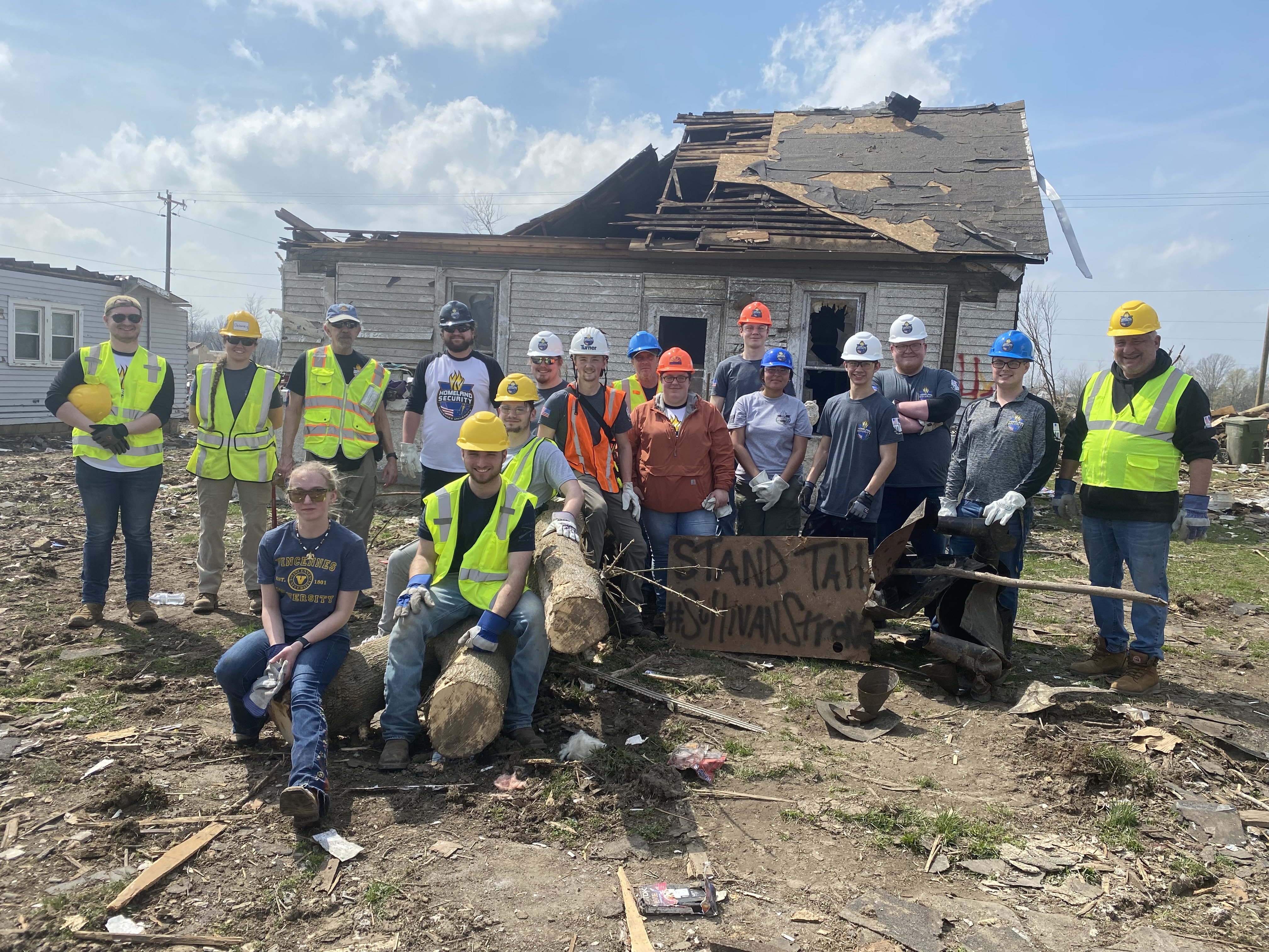 A group of VU Homeland Security student and faculty volunteers in front of tornado damage in the Sullivan, Indiana, area.