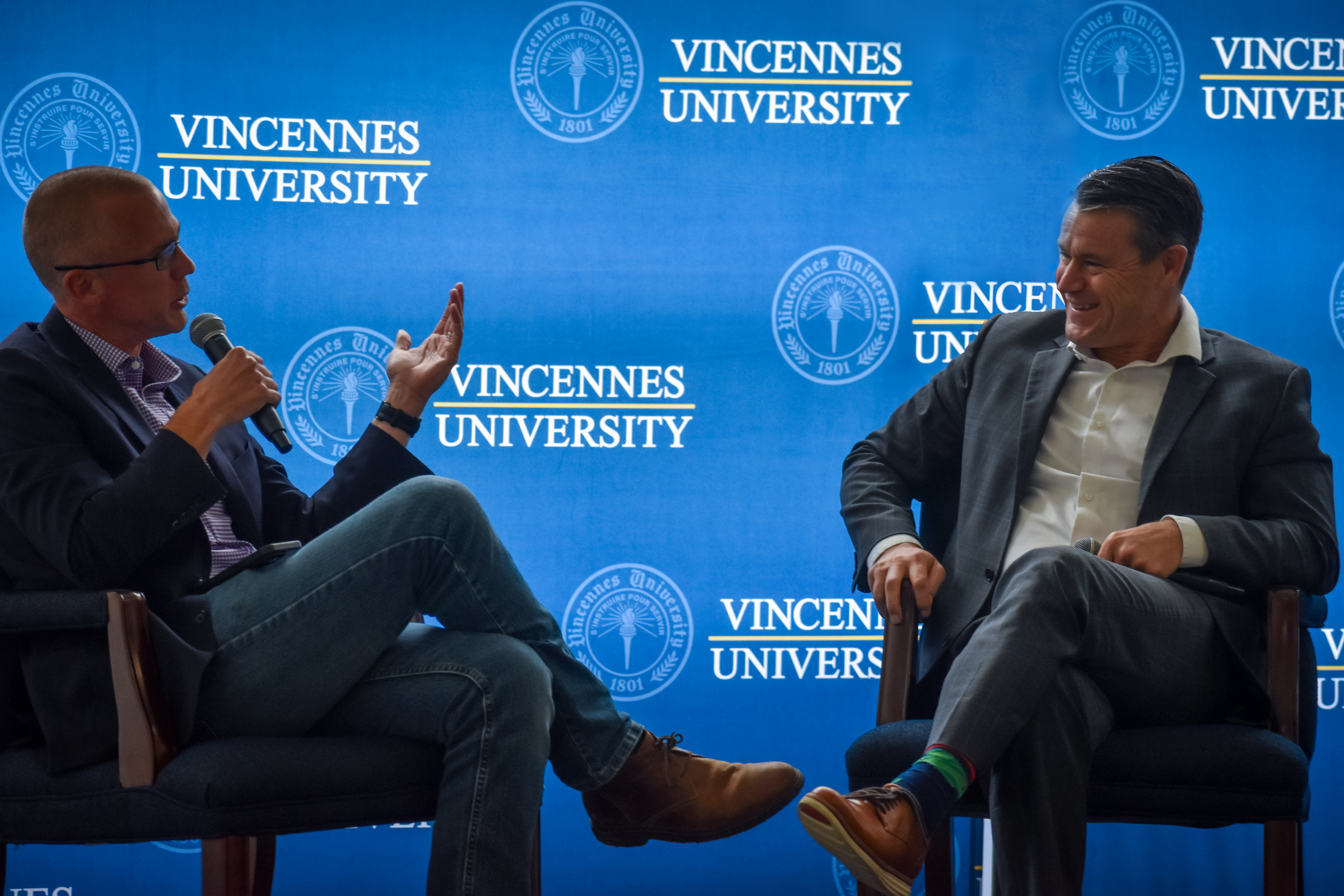 AgriNovus Indiana's Mitch Frazier and U.S. Senator Todd Young sit in chairs in front of VU backdrop during a fireside chat at VU's Agricultural Center.